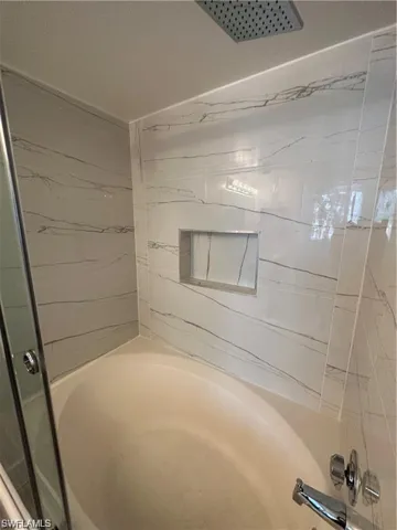 Full bathroom featuring a shower with shower door and a tub