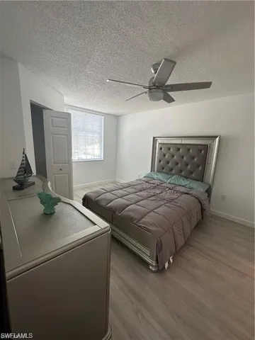 Bedroom with light wood-style floors, a textured ceiling, and ceiling fan