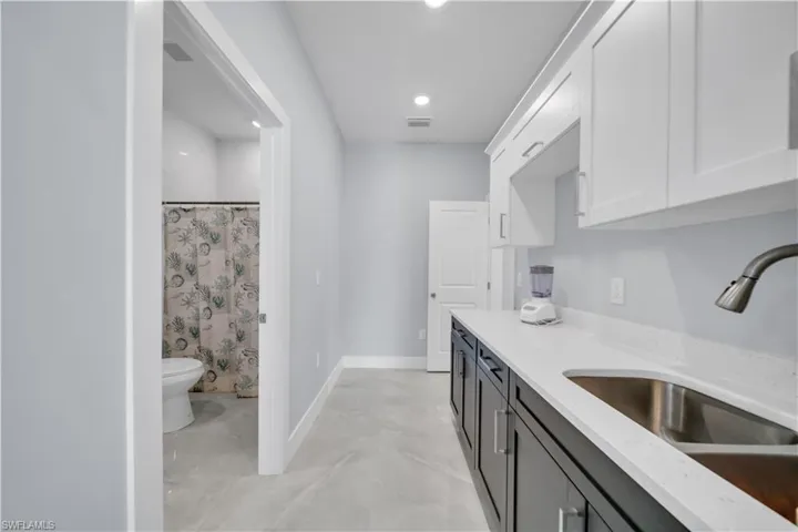Dual tone kitchen with light stone counters, two tone cabinetry, and recessed lighting