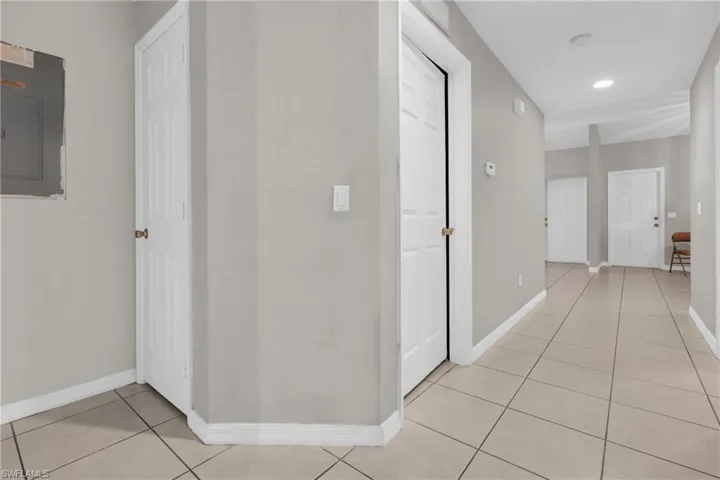 Corridor featuring electric panel, light tile patterned flooring, and recessed lighting