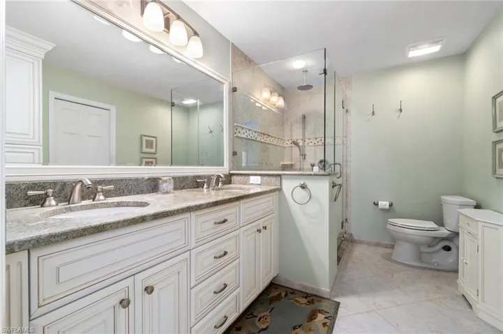 Bathroom with tile patterned floors, vanity, toilet, and walk in shower