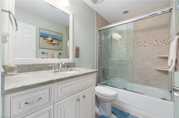 Full bathroom featuring shower / bath combination with glass door, vanity, and toilet