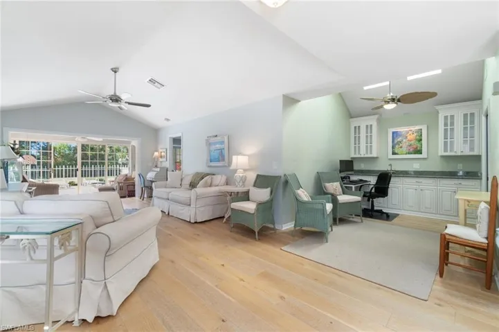 Living room featuring ceiling fan, lofted ceiling, and light wood-type flooring