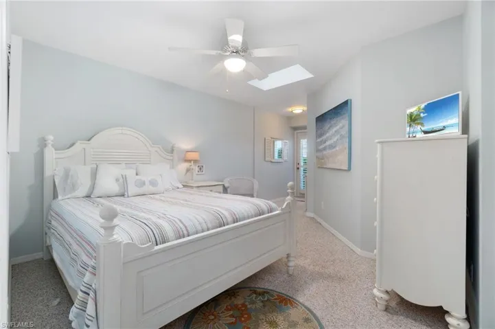 Carpeted bedroom featuring a skylight and ceiling fan