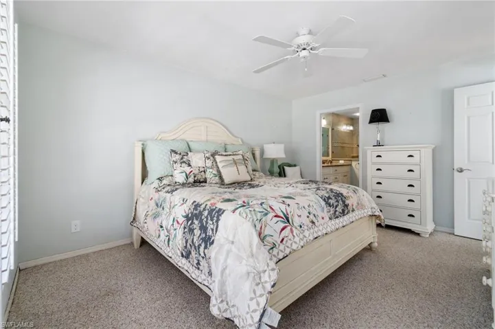 Carpeted bedroom with ensuite bath and ceiling fan