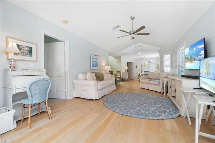 Living room with ceiling fan, light wood-type flooring, and vaulted ceiling