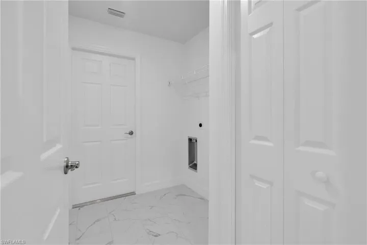 Laundry area featuring clean white walls, a durable wire shelf, and a utility hookup