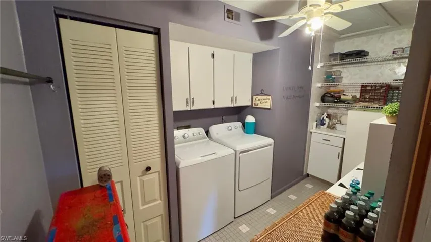 Washroom with a ceiling fan, light tile flooring, cabinet space, and separate washer and dryer. Lots of storage space with pull down attic ladder.