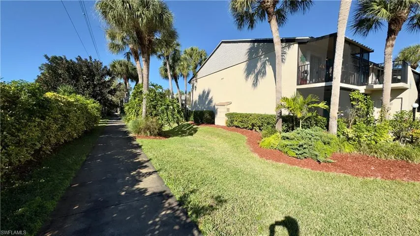 View of property exterior with stucco siding, a balcony, and a yard