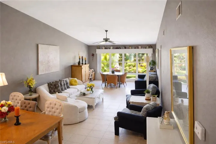 Living area featuring vaulted ceiling, ceiling fan, light tile flooring.