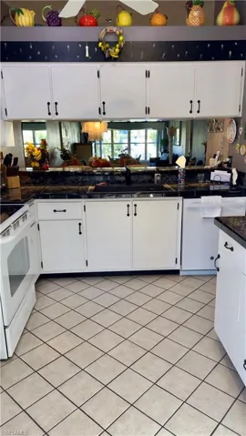 Kitchen featuring white appliances, white cabinets, backsplash, and tile countertops