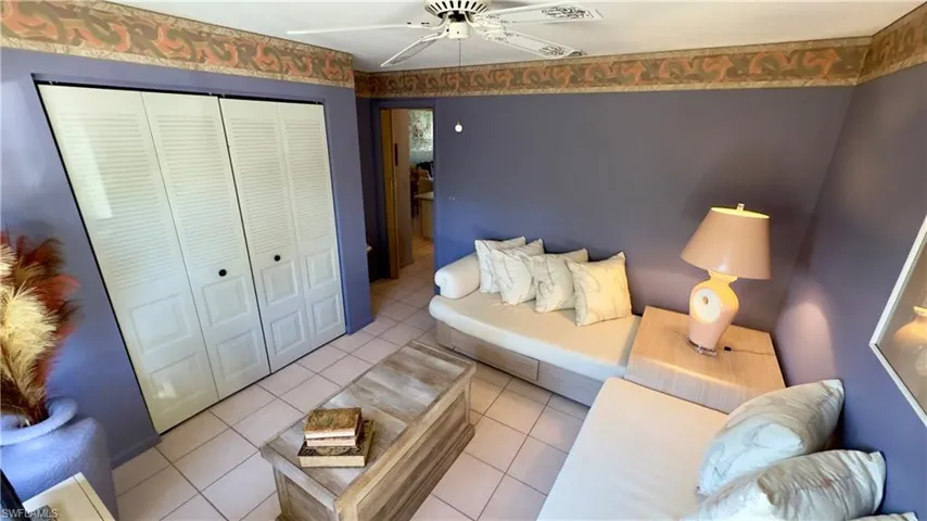 Tiled guest bedroom with a ceiling fan and large window for natural sunlight