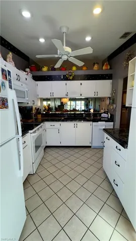 Kitchen featuring white appliances, white cabinets, backsplash, and tile countertops