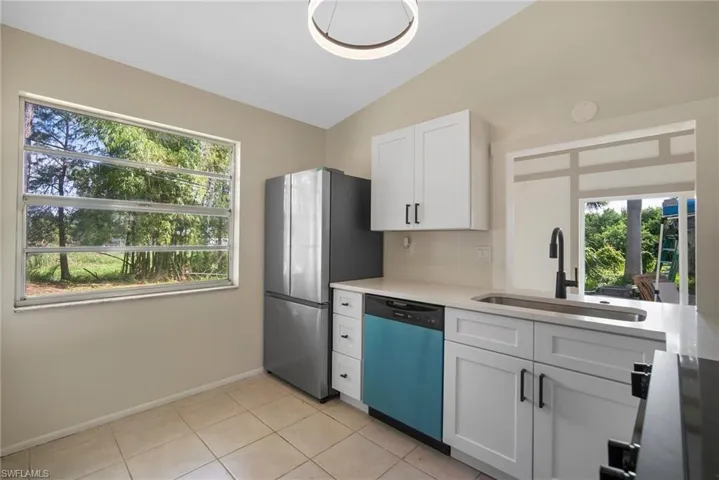Kitchen featuring a healthy amount of sunlight, appliances with stainless steel finishes, white cabinetry, and sink