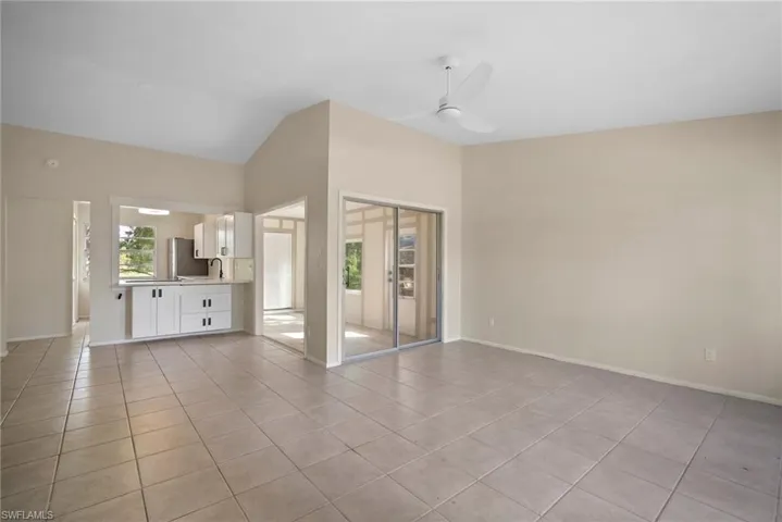 Unfurnished living room featuring ceiling fan, light tile patterned flooring, and vaulted ceiling