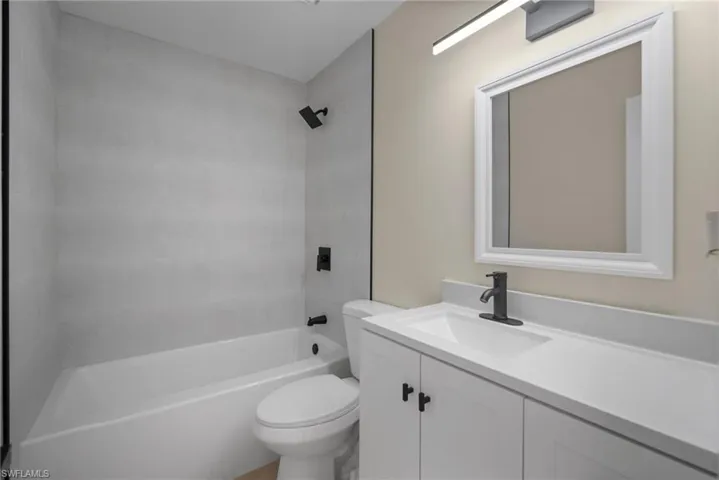 Full bathroom with toilet, tiled shower / bath combo, and vanity