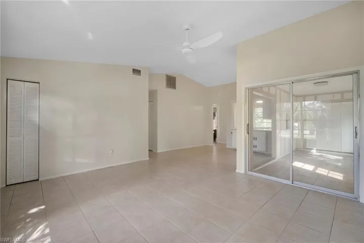 Tiled spare room with vaulted ceiling and ceiling fan