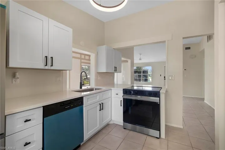 Kitchen with white cabinetry, a wealth of natural light, stainless steel appliances, and sink