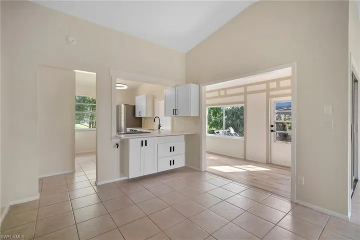 Kitchen featuring light hardwood / wood-style flooring, white cabinets, high vaulted ceiling, and sink