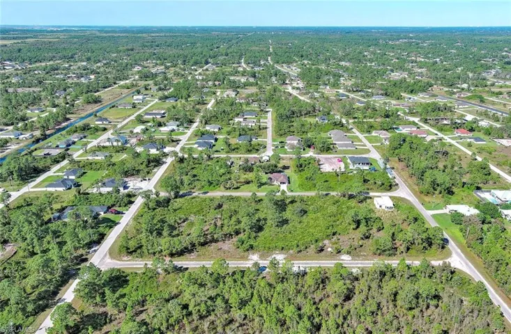 Aerial overview of property's location with a tree filled landscape and nearby suburban area