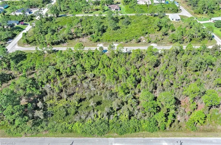 Aerial view of property and surrounding area with a forest