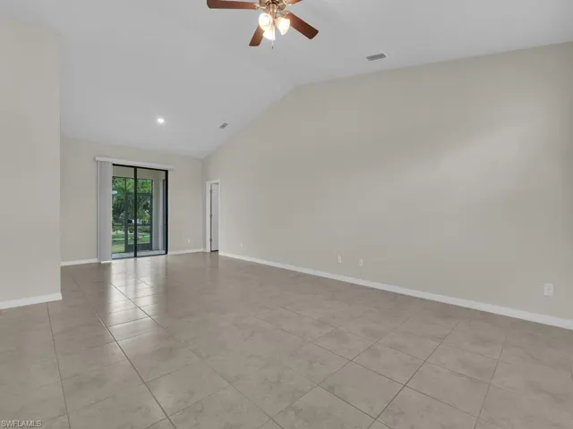 Tiled empty room with high vaulted ceiling and ceiling fan