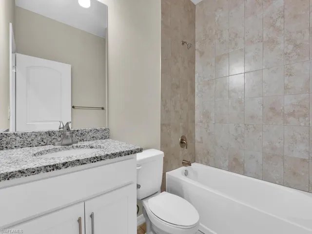 Full bathroom with tiled shower / bath, toilet, and vanity