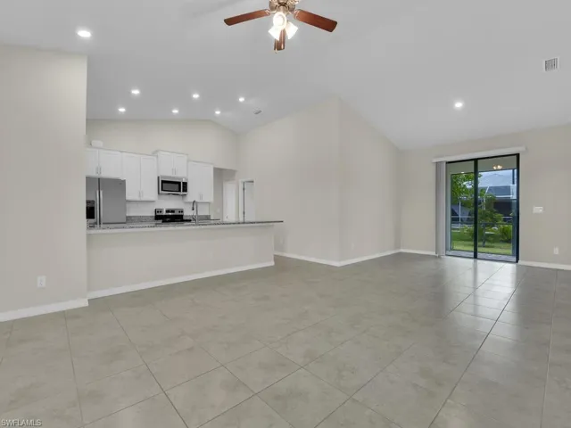 Kitchen with high vaulted ceiling, appliances with stainless steel finishes, white cabinetry, and ceiling fan