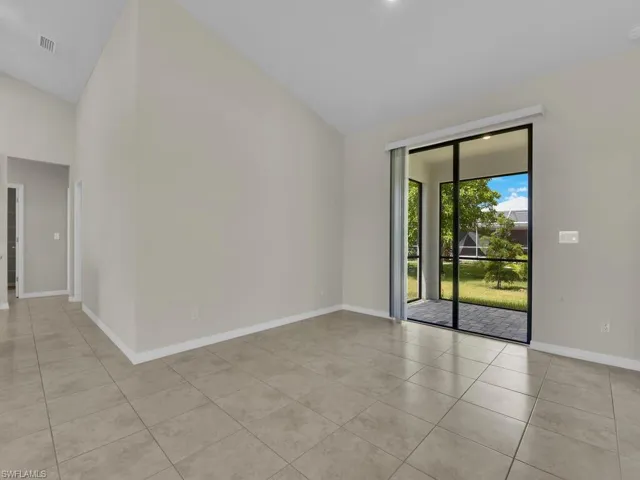 Tiled spare room featuring high vaulted ceiling