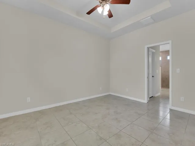 Tiled spare room featuring a tray ceiling and ceiling fan