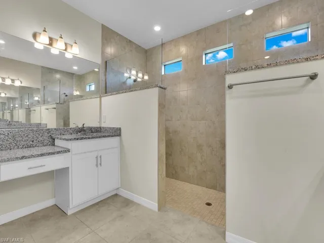Bathroom with vanity, a tile shower, and tile patterned flooring