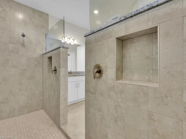Bathroom featuring tiled shower, vanity, tile walls, and tile patterned floors
