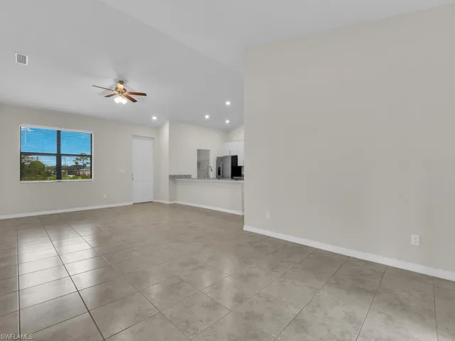 Unfurnished living room with lofted ceiling, ceiling fan, and light tile patterned floors
