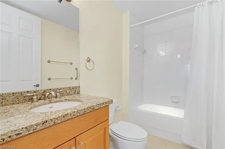 Bathroom featuring toilet, shower / bath combo with shower curtain, tile patterned flooring, and vanity