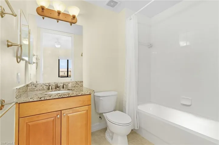 Bathroom with toilet, vanity, shower / bath combo, tile patterned flooring, and visible vents