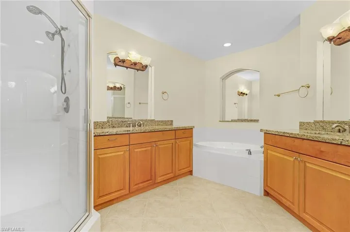 Bathroom with a stall shower, tile patterned floors, a sink, two vanities, and a bath
