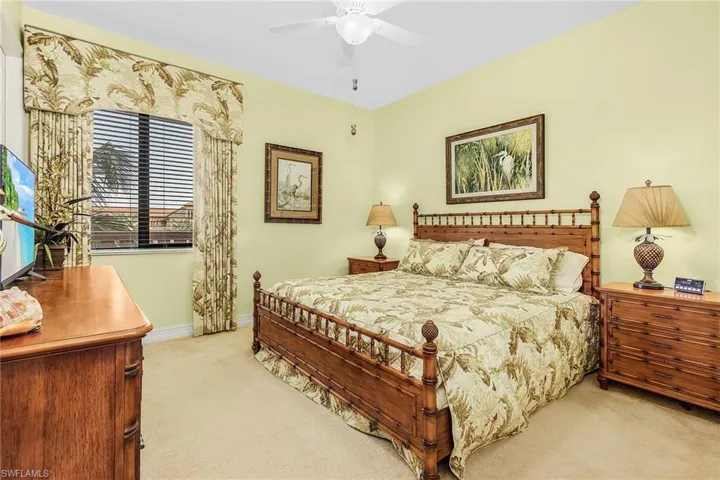 Bedroom with a ceiling fan, baseboards, and light colored carpet