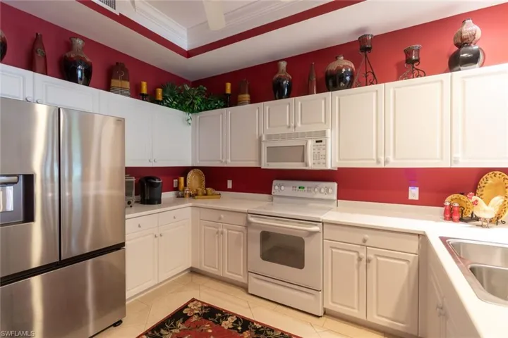 Kitchen featuring white appliances, light countertops, white cabinetry, and ornamental molding