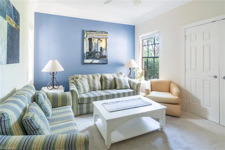 Carpeted living room with crown molding and ceiling fan