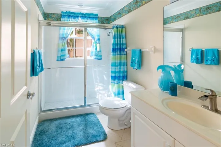 Bathroom featuring a stall shower, vanity, light tile patterned floors, and crown molding