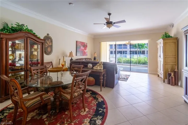 Dining area with light tile patterned floors, crown molding, and a ceiling fan