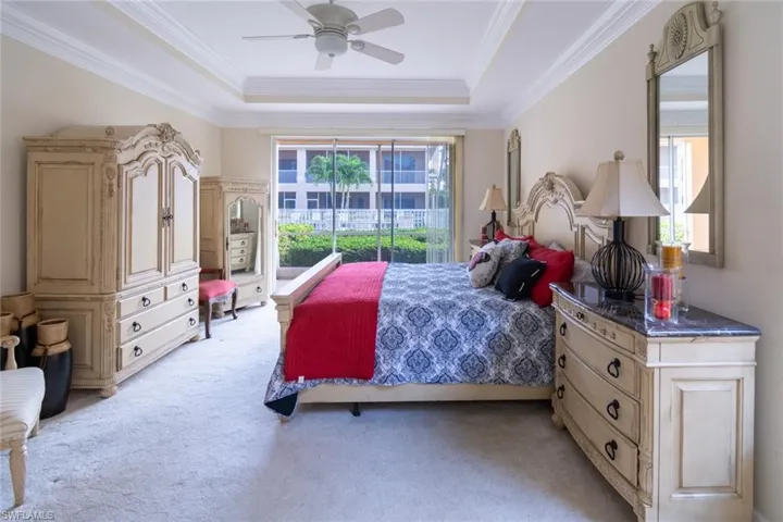 Bedroom featuring a raised ceiling, light colored carpet, access to outside, crown molding, and ceiling fan