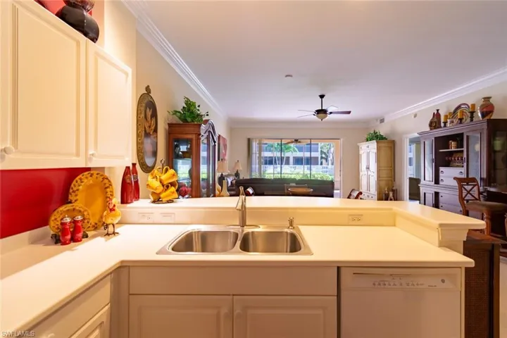 Kitchen featuring a peninsula, open floor plan, crown molding, dishwasher, and light countertops