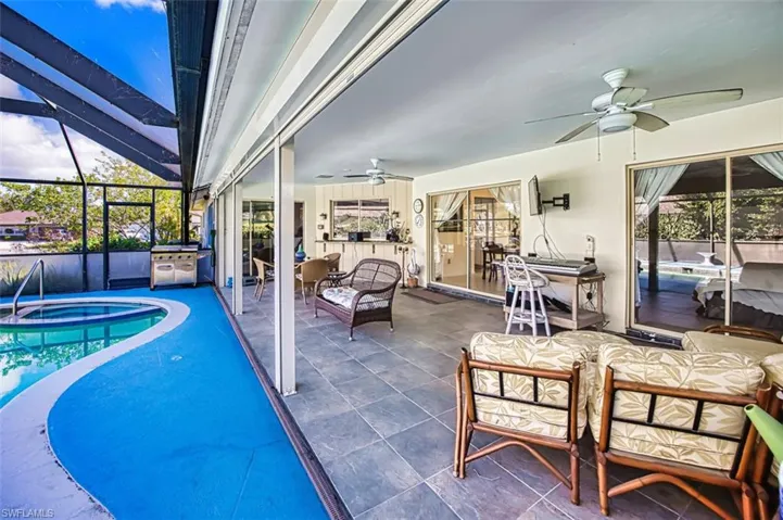 View of pool with a patio, a sunroom, a pool with connected hot tub, outdoor dining area, and a lanai