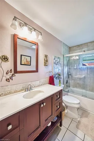 Bathroom with vanity, enclosed tub / shower combo, and light tile patterned floors