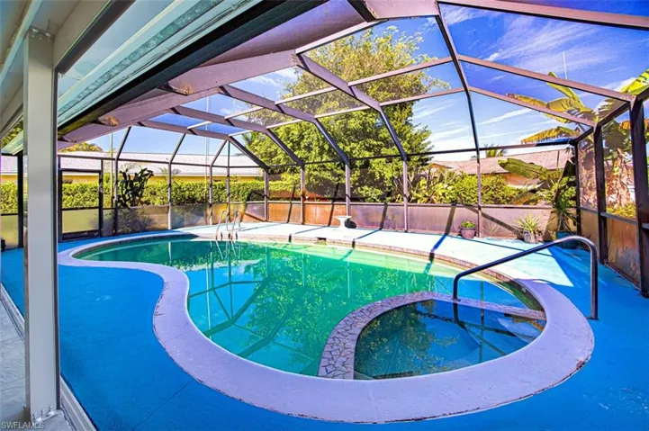 View of pool featuring a lanai, a pool with connected hot tub, a sunroom, and a patio area