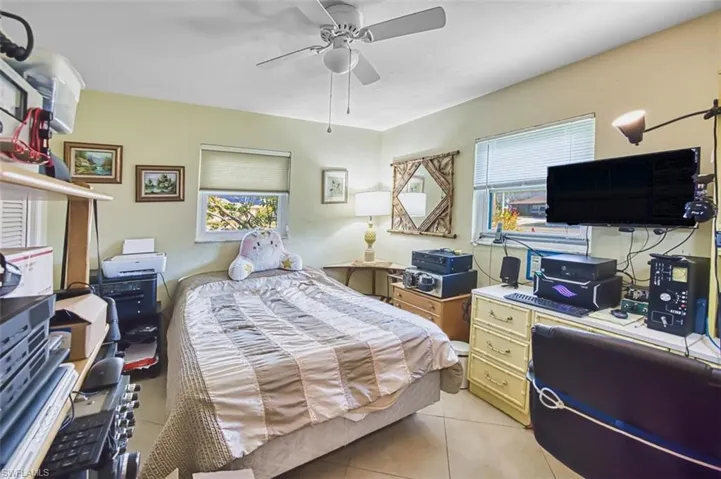 Bedroom featuring light tile patterned floors, a ceiling fan, and a desk