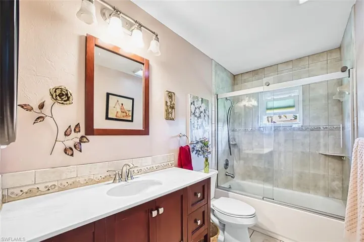 Full bath with vanity, bath / shower combo with glass door, and light tile patterned floors