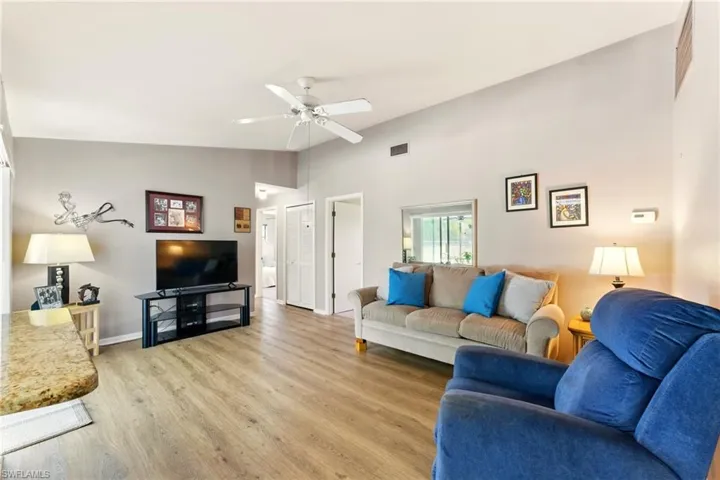 Living room with lvp flooring, a ceiling fan, and high vaulted ceiling