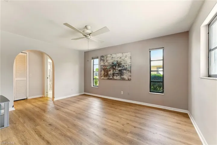 Unfurnished room with arched walkways, plenty of natural light, and lvp flooring